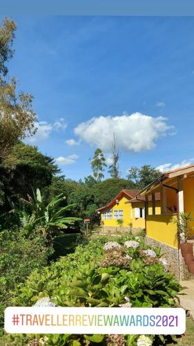 a yellow house with a garden in front of it at Pousada Polessas in Visconde De Maua
