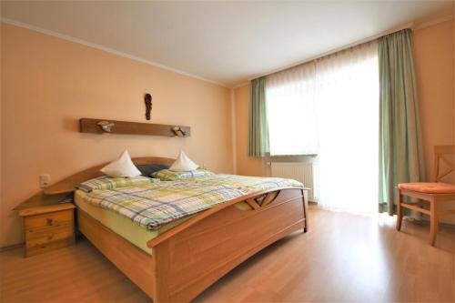 ein Schlafzimmer mit einem Bett, einem Fenster und einem Stuhl in der Unterkunft Appartementhaus Sonneneck in Bad Füssing