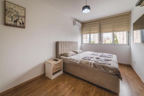 sypialnia z łóżkiem, komodą i oknami w obiekcie Renta stan apartman odmor w mieście Podgorica