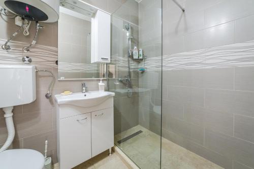 ein Bad mit einer Dusche, einem Waschbecken und einem WC in der Unterkunft Renta stan apartman odmor in Podgorica