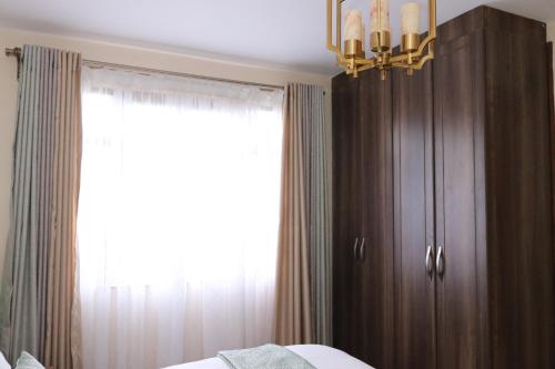 a bedroom with a bed and a window and a chandelier at Glamour Suites in Nanyuki