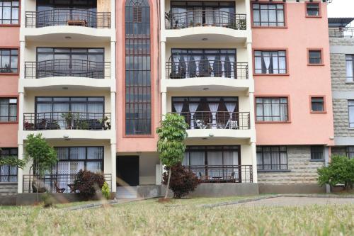 um prédio de apartamentos com uma árvore em frente em Glamour Suites em Nanyuki