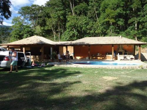 a house with a pool and people sitting in the yard at Recanto beira rio in Sana