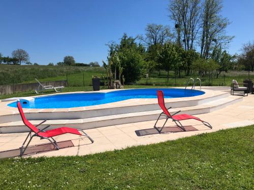una piscina con 2 sillas rojas enfrente en Petite Maison de campagne dépaysante, en Velet