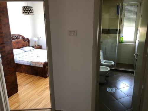 a bedroom with a bed and a bathroom with a toilet at Square apartment Podgorica in Podgorica
