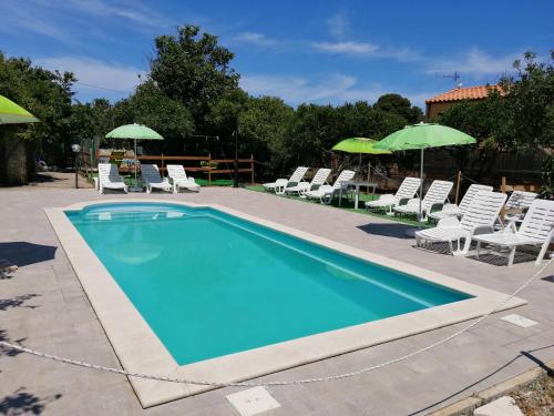 a swimming pool with chairs and umbrellas at House Cefalù 1915 in Lascari