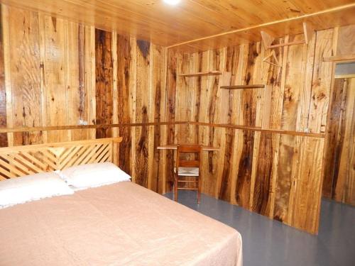 a bedroom with a bed and wooden walls at Pousada Rural Paiol dos Pellizzaro in Concordia