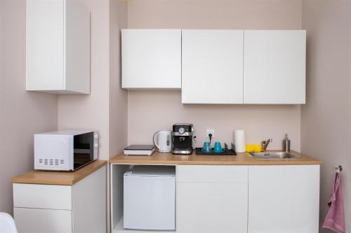 cocina con armarios blancos, microondas y fregadero en APARTAMENTwPUCKu, en Puck