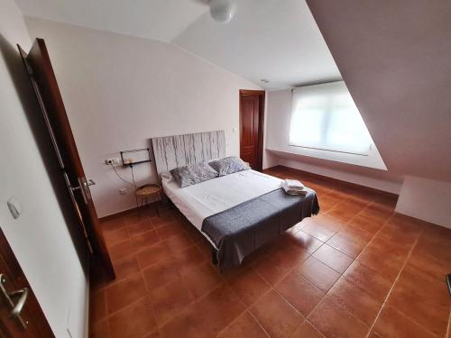 Schlafzimmer mit einem Bett und einem Fenster in der Unterkunft Piso Don Ramón in Razo