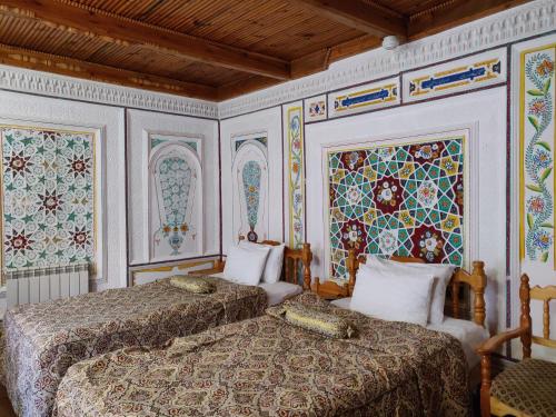 two beds in a room with mosaics on the walls at Sasha & Son Hotel in Bukhara