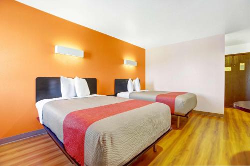 two beds in a room with orange walls and wooden floors at Motel 6-Truth Or Consequences, NM in Truth or Consequences