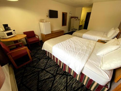 a hotel room with two beds and a chair at Woodland Inn & Suites in Medford