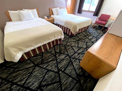 a hotel room with two beds and a chair at Woodland Inn & Suites in Medford