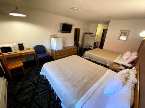 a hotel room with two beds and a desk at Woodland Inn & Suites in Medford