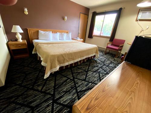 a hotel room with a bed and a tv at Woodland Inn & Suites in Medford