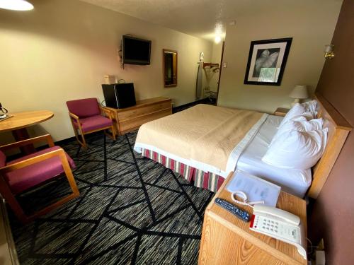 MedfordにあるWoodland Inn & Suitesのベッド、テーブル、椅子が備わるホテルルームです。