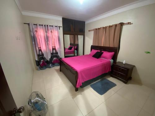 a bedroom with a pink bed and two pink chairs at Oasis de paz in Jarabacoa