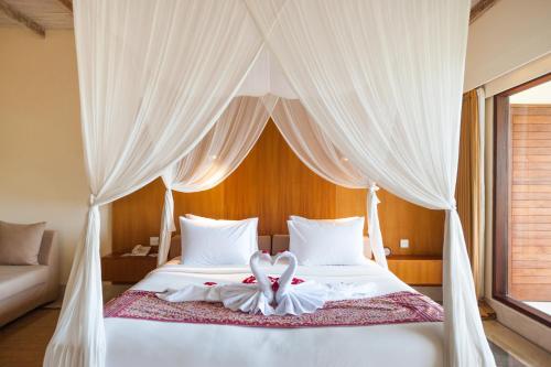 a bedroom with a bed with a heart decoration on it at Komaneka at Monkey Forest Ubud in Ubud