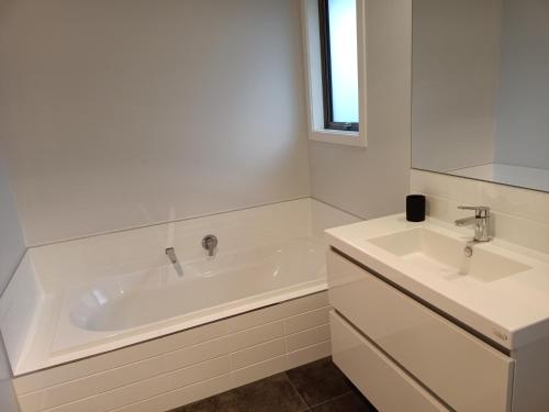 Baño blanco con bañera y 2 lavabos en Richmond, Nelson 3brm New Home, en Richmond