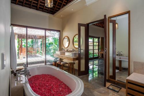 كومانيكا أت مونكي فوريست في أوبود: حمام مع حوض استحمام مليء بالورود الحمراء