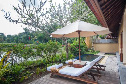 an outdoor patio with an umbrella and a pool at Komaneka at Monkey Forest Ubud in Ubud
