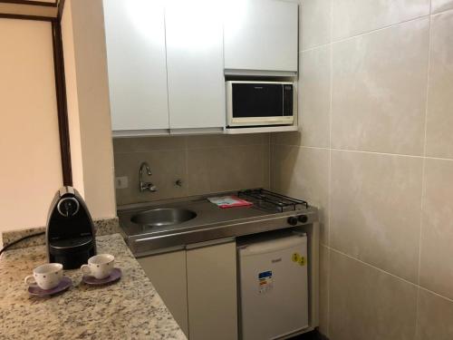 eine kleine Küche mit einer Spüle und einer Mikrowelle in der Unterkunft Apartamento no itaim bibi 264 localização perfeita in São Paulo