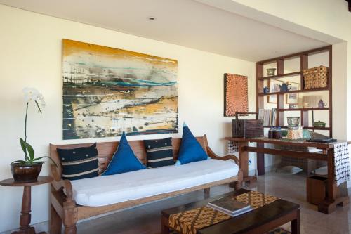 a living room with a couch with blue pillows at Komaneka at Monkey Forest Ubud in Ubud