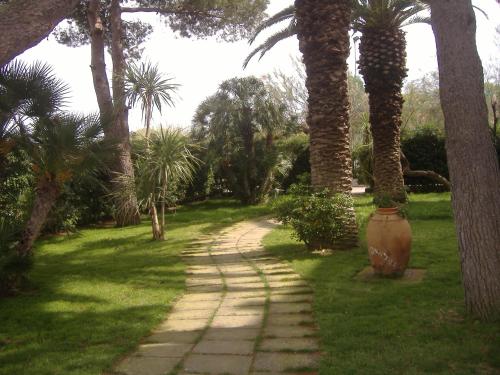 a dirt road with palm trees and a large vase at Ecoresort Le Sirene - Caroli Hotels in Gallipoli