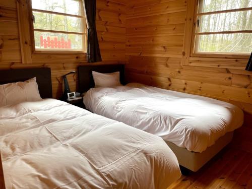 two beds in a log cabin with two windows at Haramura CAFE Lodge - Vacation STAY 33104v in Hara