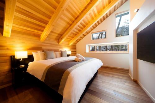 a bedroom with a large bed with a wooden ceiling at Asagiri Chalet Hakuba in Hakuba