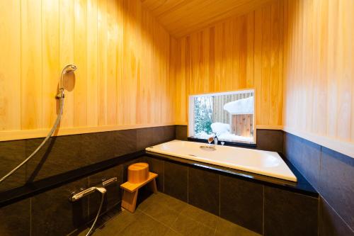a bathroom with a tub and a sink and a shower at Asagiri Chalet Hakuba in Hakuba