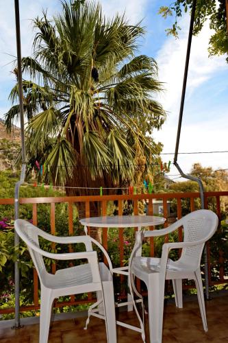 a table and chairs on a porch with a palm tree at Lissos Rooms Sougia in Sougia