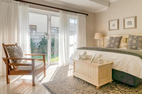 a bedroom with a bed and a chair and a window at Bela Rini Guesthouse in Bela-Bela