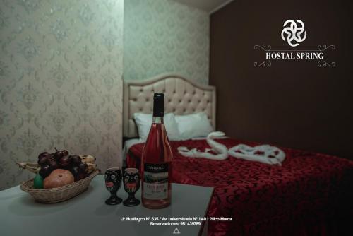 a bottle of wine and a basket of fruit on a bed at Hostal Spring II in Huánuco