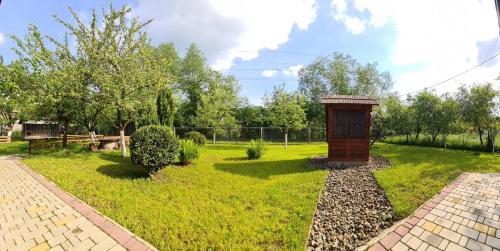 a garden with a wooden structure in the grass at Usadba Okhotnichiy Dvor in Yabluniv