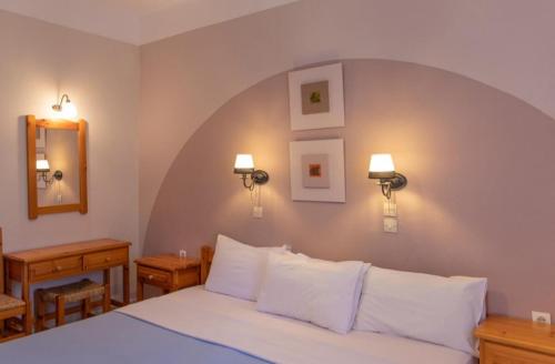 1 dormitorio con 1 cama grande con almohadas blancas en Limnonari Beach Rooms, en Skopelos Town