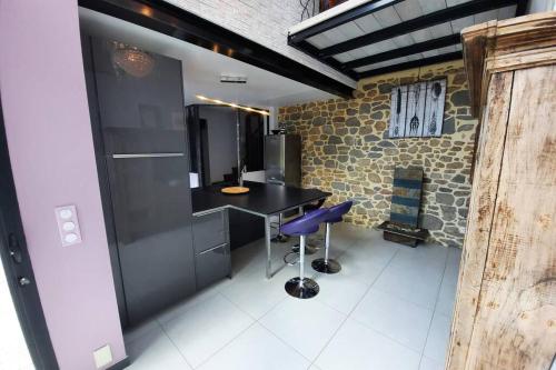 une cuisine avec un comptoir noir et un tabouret bleu dans l'établissement Maison Jeanne (proche Bécherel pour 14 personnes), à Saint-Pern