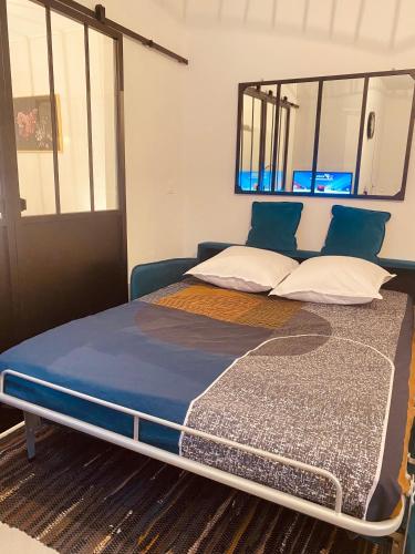 Cette chambre comprend un grand lit avec des oreillers bleus et blancs. dans l'établissement L’Atelier, Appartement rénové à 100 mètres du Canal, à Sète