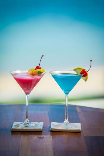 two cocktails sitting on top of a wooden table at White Whale Beachfront Pool Villa in Ban Bang Po