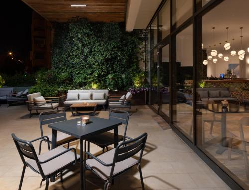 a patio with tables and chairs and a green wall at Cassia Hotel Jerusalem in Jerusalem