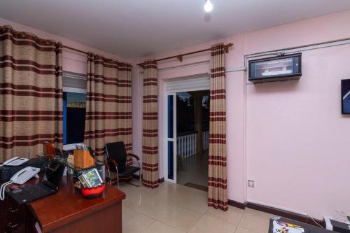 a room with a desk and a tv on a wall at Karibu BB Suites in Entebbe