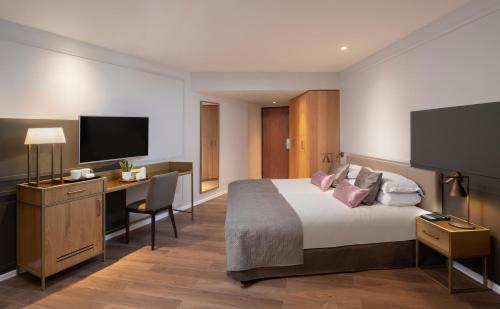 a hotel room with a bed and a desk and a tv at Cassia Hotel Jerusalem in Jerusalem