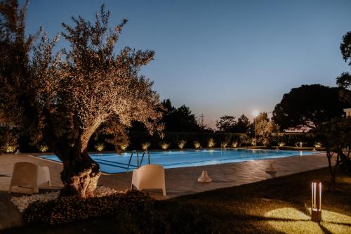 a swimming pool with a tree and chairs next to it at SALAPIA SALIS RESORT in Margherita di Savoia