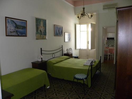 1 dormitorio con 2 camas verdes y ventana en Novecento en Lipari