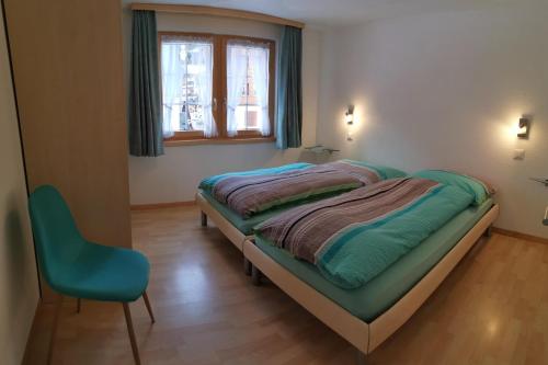 a bedroom with a bed and a blue chair at Ferienhaus Antigua in Saas-Grund