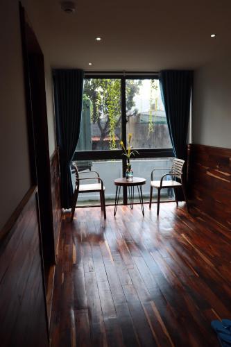 a living room with a table and chairs and a large window at Amacon Hotel & Coffee in Buôn Kô Sir