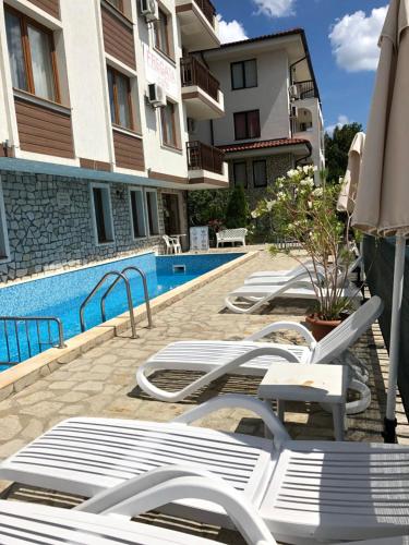 a row of lounge chairs next to a swimming pool at Fregata Complex Marina in Sveti Vlas