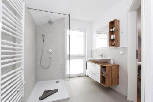 a white bathroom with a shower and a sink at Blauwasser Luv in Zingst