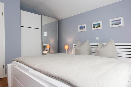 a white bedroom with a large white bed at Blauwasser Luv in Zingst