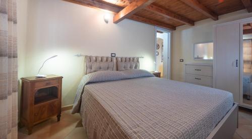 1 dormitorio con 1 cama y mesita de noche con lámpara en Casa Vacanze " IS MERIS " en Capitana